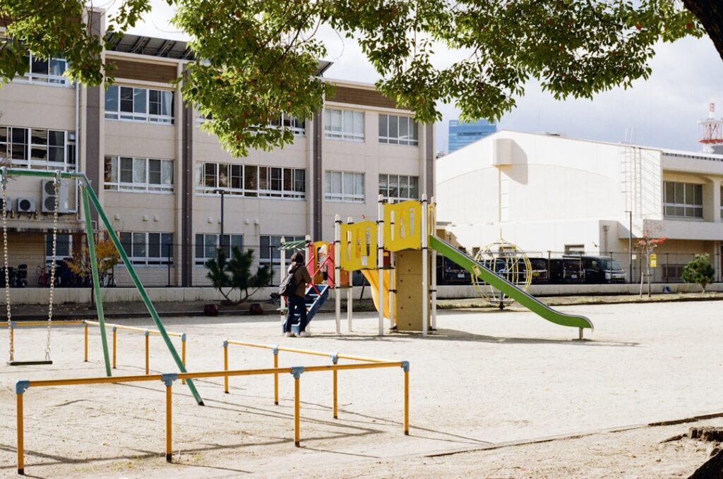 Groupe d'enfants de 8-10 ans participent activement à des jeux collectifs dans une cour d'école aménagée avec équipements variés et zones de jeu délimitées