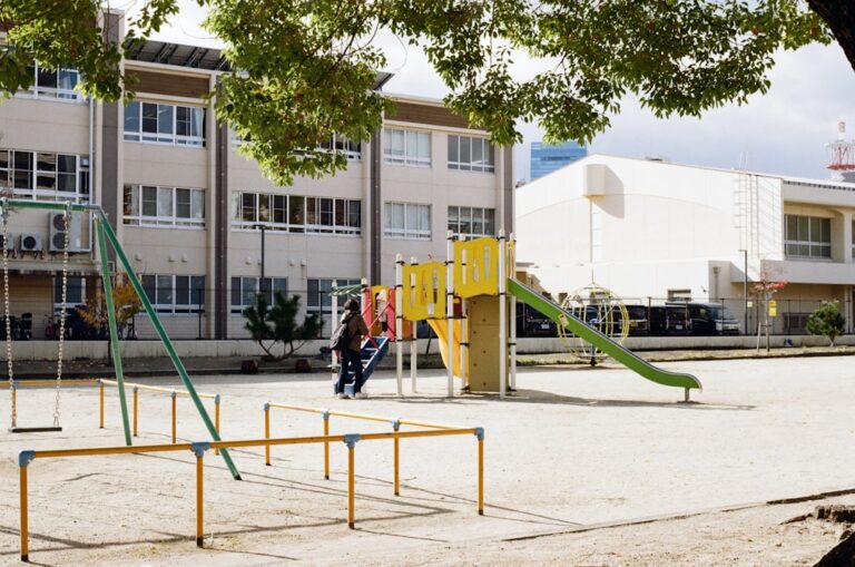 Groupe d'enfants de 8-10 ans participent activement à des jeux collectifs dans une cour d'école aménagée avec équipements variés et zones de jeu délimitées